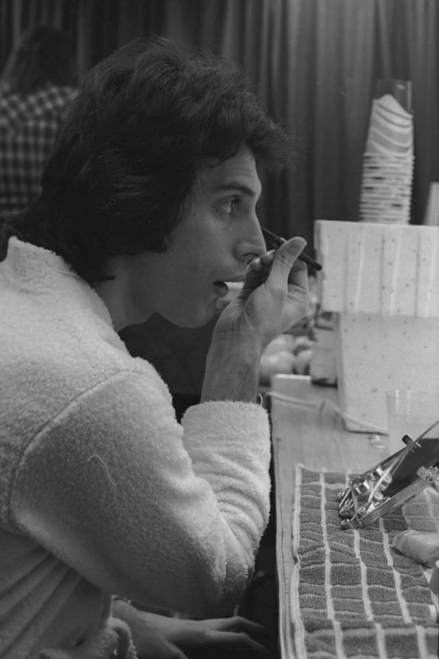 Freddie Mercury of Queen applies make-up backstage before a concert in the US, January 1977