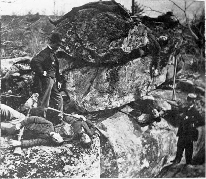 Men examine the bodies of two dead sharpshooters.