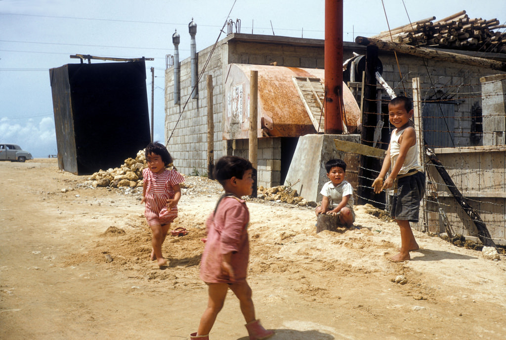 Children play with a sand pile, Okinawa, 1950s