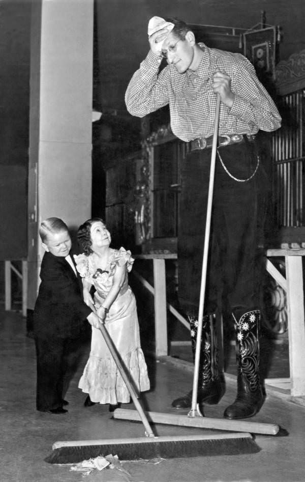 American silent film actor and sideshow performer Jack Earle shares sweeping duties with two members of the Doll family while on tour with the Ringling Brothers/Barnum and Bailey Circus, 1938