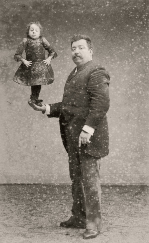 Dutch midget Johanna Pauline Musters, a.k.a. "Princess Pauline," "Lady Dot" or the "Midget Mite," standing on the hand of her manager Verschueren, 1890