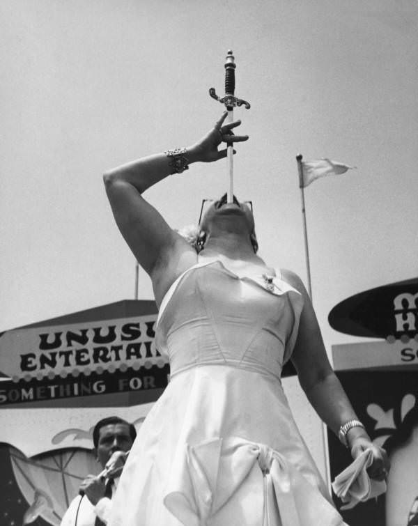 A circus woman performs a sword swallowing trick