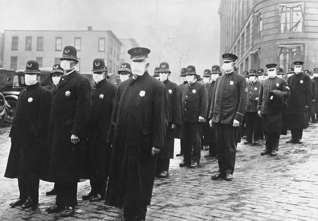 Policemen stand in a street in Seattle, Washington, wearing protective masks made by the Seattle Chapter of the Red Cross, during the influenza epidemic in 1918.