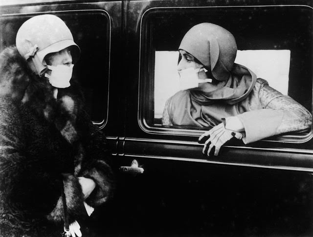 Two women speak through flu masks during the epidemic, 1918.