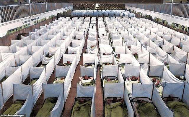 Hospital beds crammed head to toe at the San Francisco Naval Training Station. They are occupied by soldiers.
