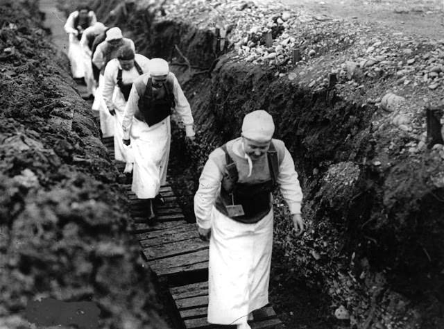 American nurses carrying gas masks walk through a trench in France, 1918.