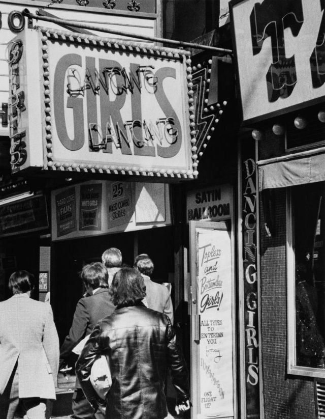 Men walking past the entrance to one of the strip clubs around Times Square, New York City, 1975.