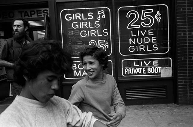 Two teenage hustlers walk by an x-rated video store in Times Square that offered nude girls for 25 cents.