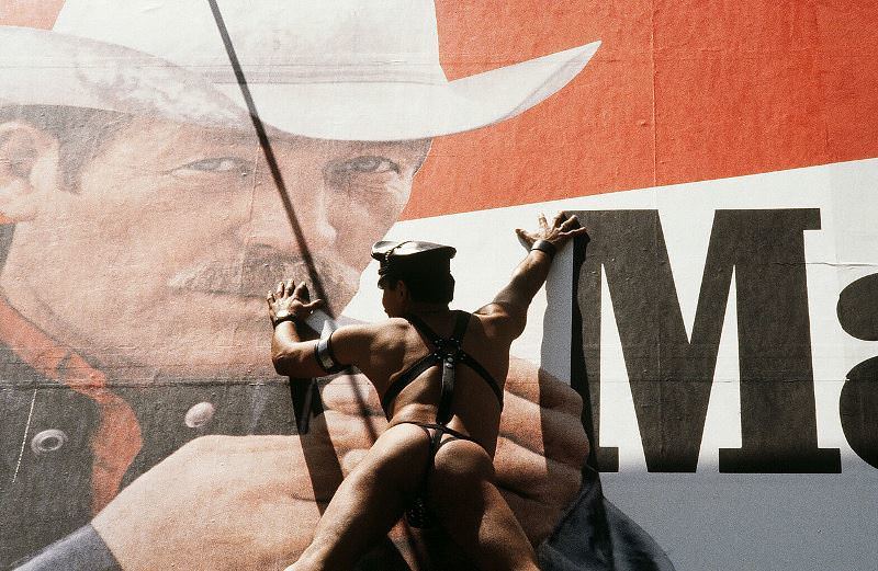 A man adorning only a leather hat and thong scales a Marlboro billboard on 44th Street in 1980.