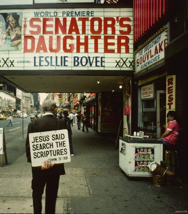 A Christian proselytizer walks in front of an adult theater on 8th Avenue.