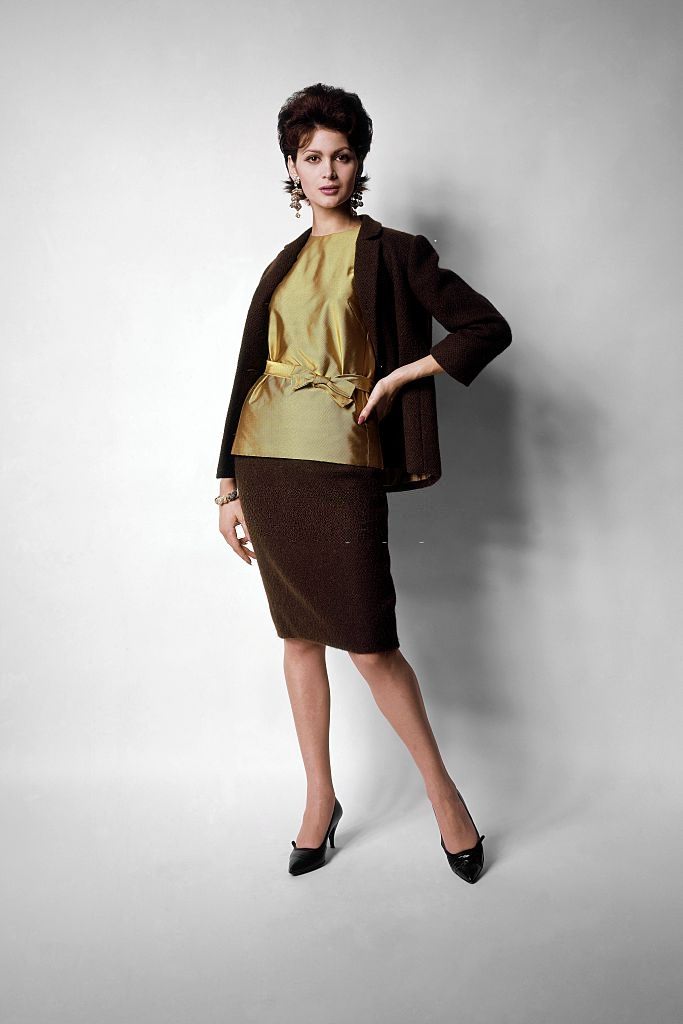 Model wearing green-tea wool suit with lemon colored silk twill overblouse, tied at the waist, Vogue 1961