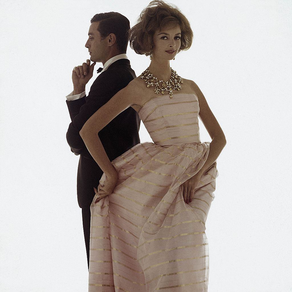 Fashion model in a ball gown of pink organza and gold lurex-striped with matching stole, Glamour 1961