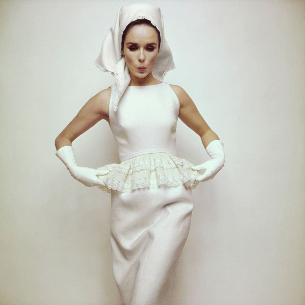 Model wearing white 'peplum of lace' on white sleeveless dress, Vogue 1963