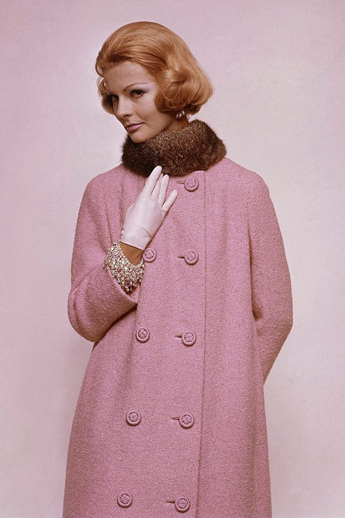 Fashion Model wearing collarless tweed coat in wool with cord buttons, Georges Kaplan opossum fur ruff with sequined sheath of silk chiffon beneath by Anne Fogarty, Glamour 1960