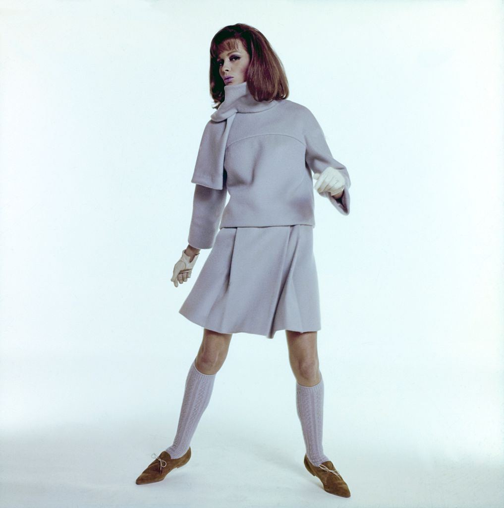 Model wearing lite blue two piece skirt ensemble with cowl neck and pleated skirt, Vogue 1964