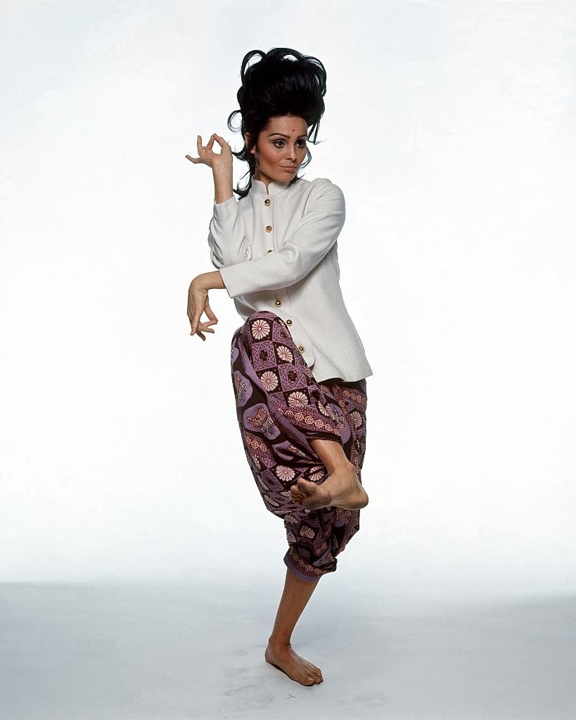 Israeli actress Daliah Lavi stands in Thai Dance pose, wearing Rudi Gernreich's white jacket, Vogue 1965