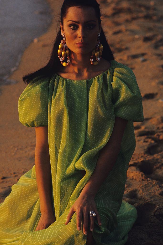 Israeli actress and model Daliah Lavi kneeling on beach, wearing voluminous peignoir green with white polka dots, Vogue 1965