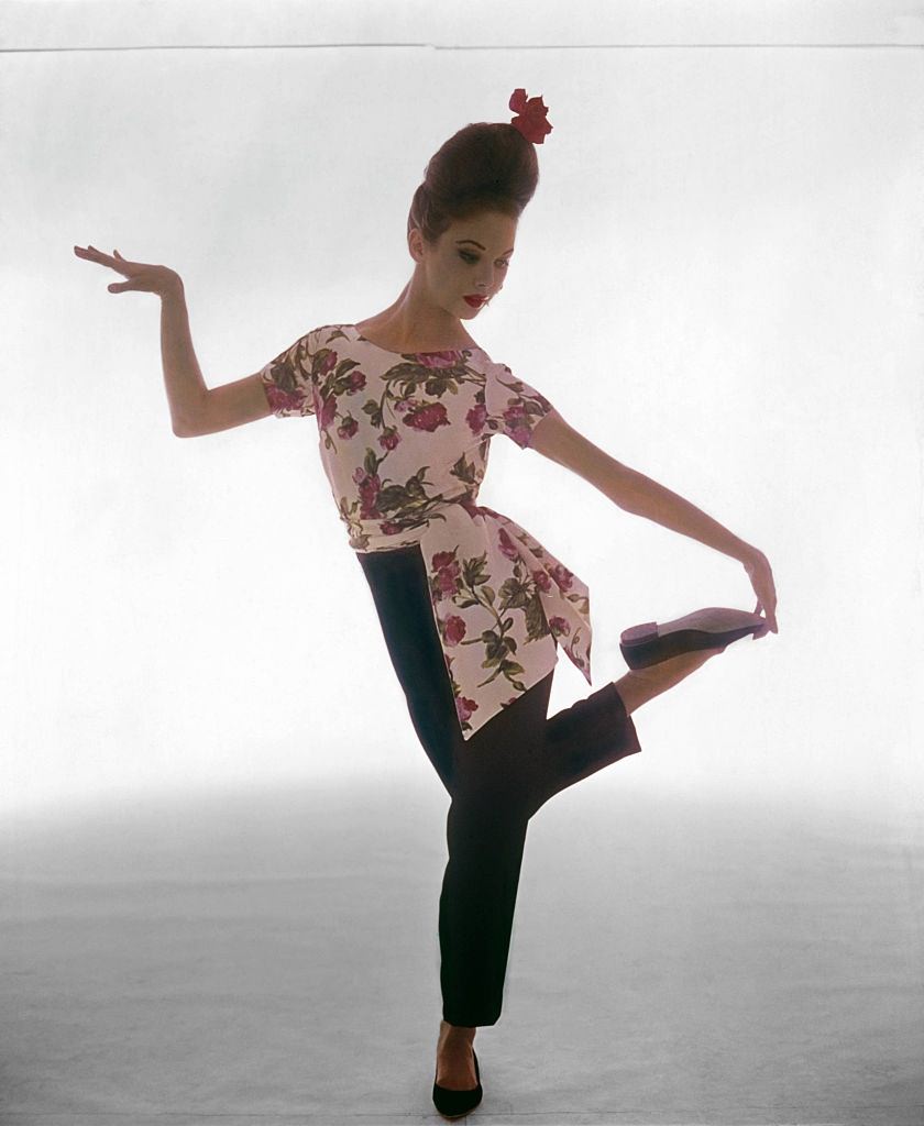 NYC Ballet dancer, Allegra Kent wearing a hostess pajama of black silk velvet pants with a white silk top printed with pink and red roses, Vogue 1961