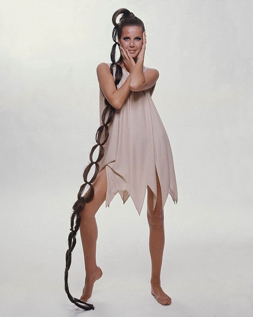 Model sporting floor-length hairpiece wearing sleeveless jagged-hem dress, Vogue 1966