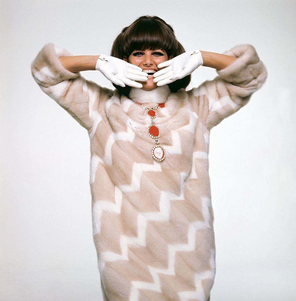 Actress Claudia Cardinale wearing pale brown mink coat laced with white mink diagonals, Vogue 1966