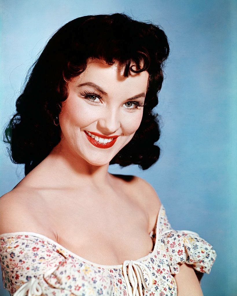 Debra Paget wearing an off-the-shoulder dress, 1955