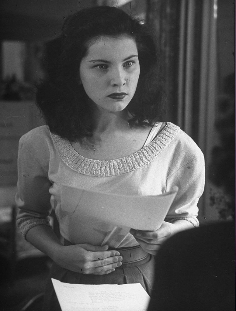 Debra Paget wearing a lacy off-the-shoulder dress and long earrings, 1957