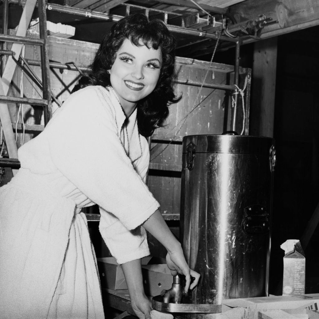 Debra Paget helps herself to coffee on the set of the Panoramic Productions film 'The Gambler from Natchez', 1954