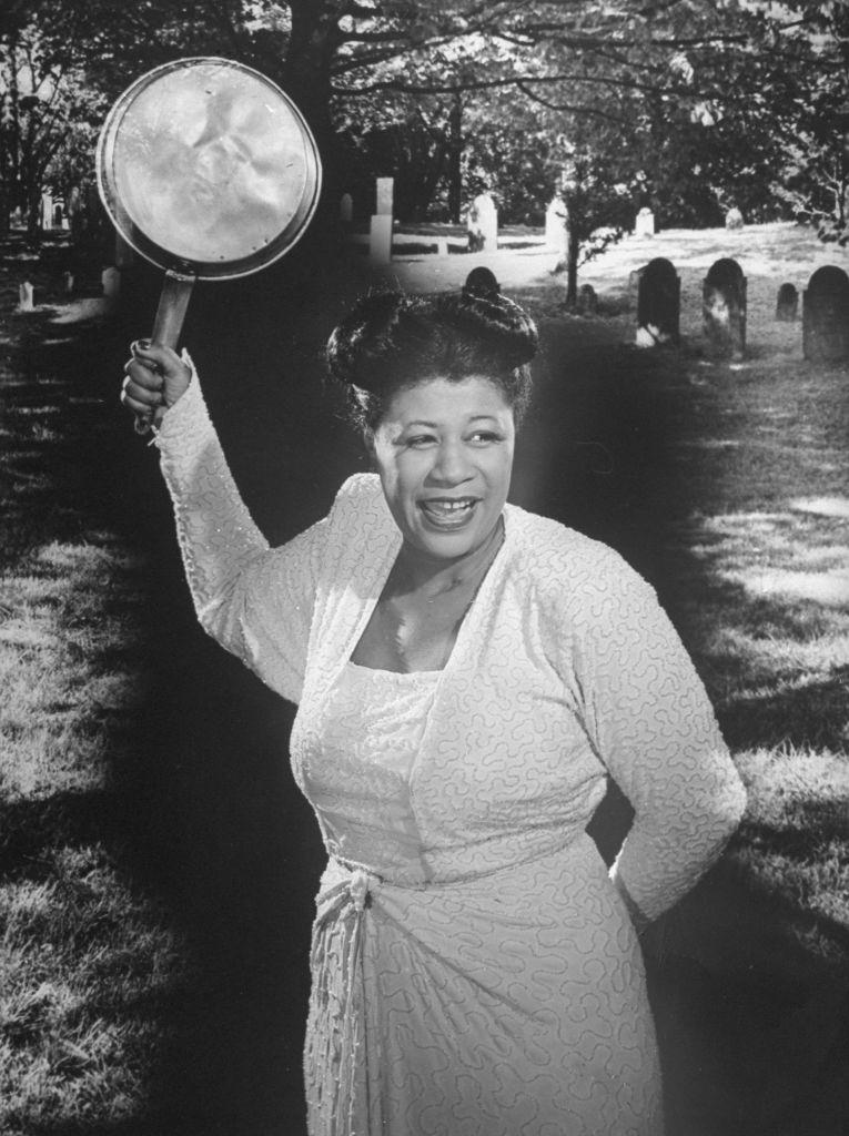 Ella Fitzgerald wielding a saucepan while standing in a cemetery singing Stone Cold Dead in the Market, as a promo for one of the hit songs of the day