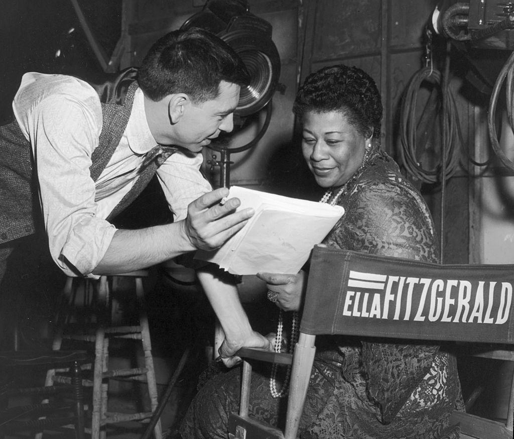 Ella Fitzgerald with Jack Webb discussing a script on the set of Webb's film, 'Pete Kelly's Blues,' in which Fitzgerald had a role, 1955