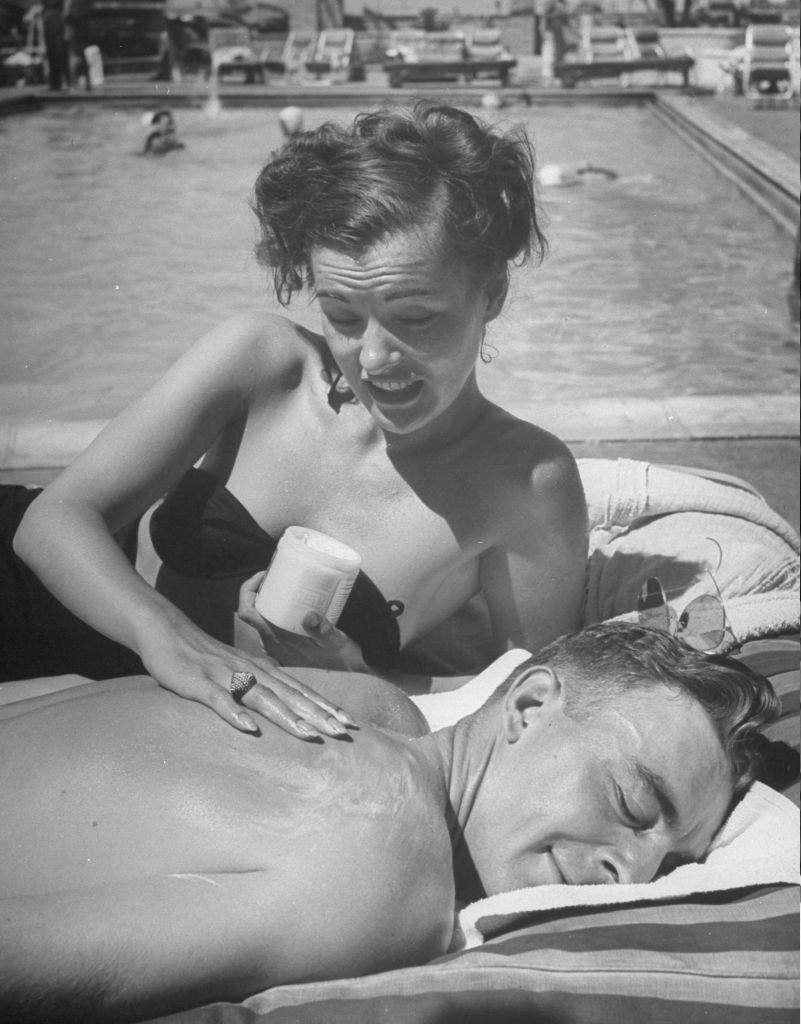 Ella Raines rubbing sunblock on the shoulder of his husband, Major Kenneth Trout