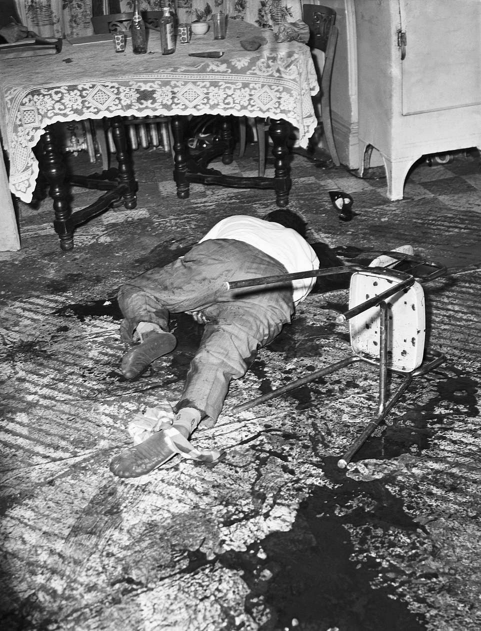 This Bronx killing took place in 1962. The shoeless victim was found covered in blood sprawled across a living room floor after being shot in his chair