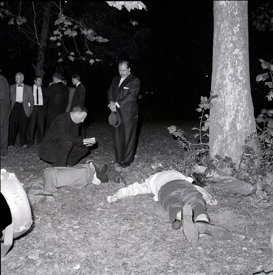 A priest attending the bodies of Thomas J Hogan and Fred Romer in 1961. Hogan shot dead Romer before turning the gun on himself