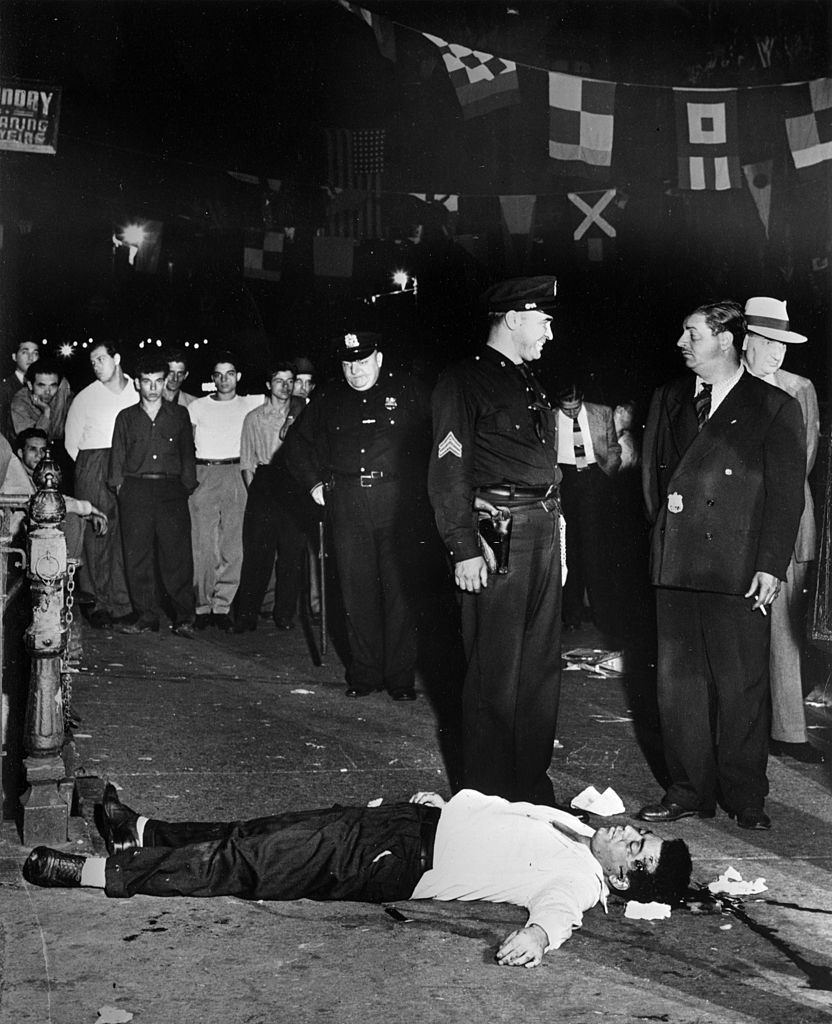 A murder at the feast of San Gennaro. Police take over at the scene of a gang killing at 119 Mulberry Street, in the heart of Little Italy, New York. The two victims were Joseph 'Little Joe' La Cava and Rocco 'Chickee' Fagio.