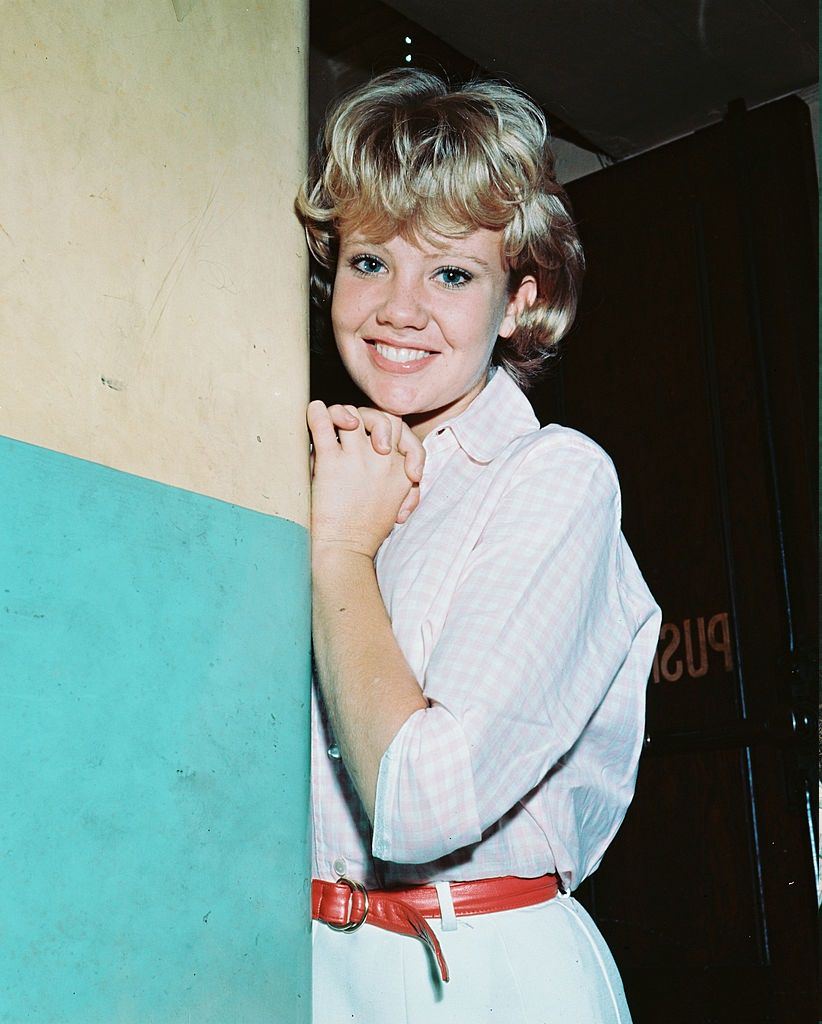 Hayley Mills wearing a white dress, tie around the waist with a red belt, 1960