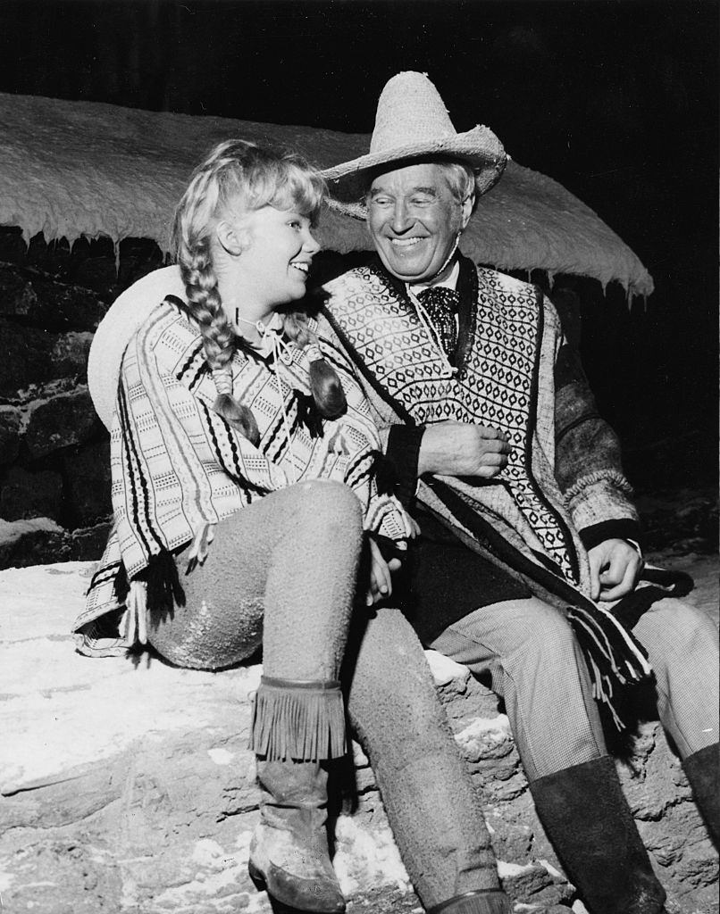 Hayley Mills and Maurice Chevalier, laughing during filming, on the set of the film 'In Search of the Castaways', 1961