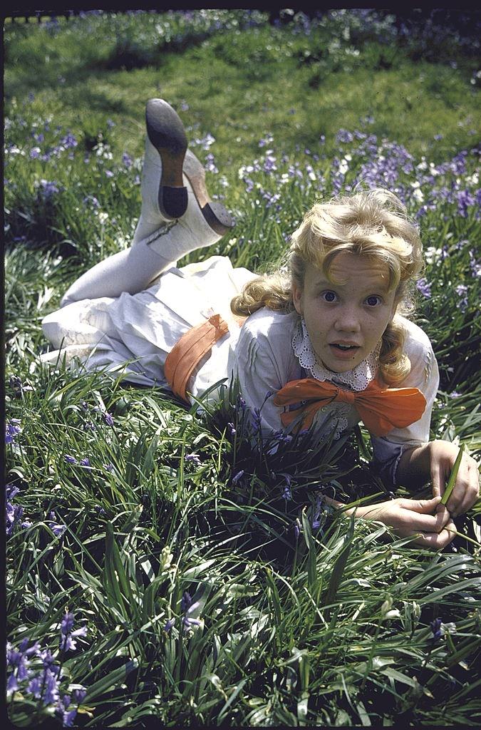 Hayley Mills in old-fashioned dress lying on grass during the production of the movie Pollyanna
