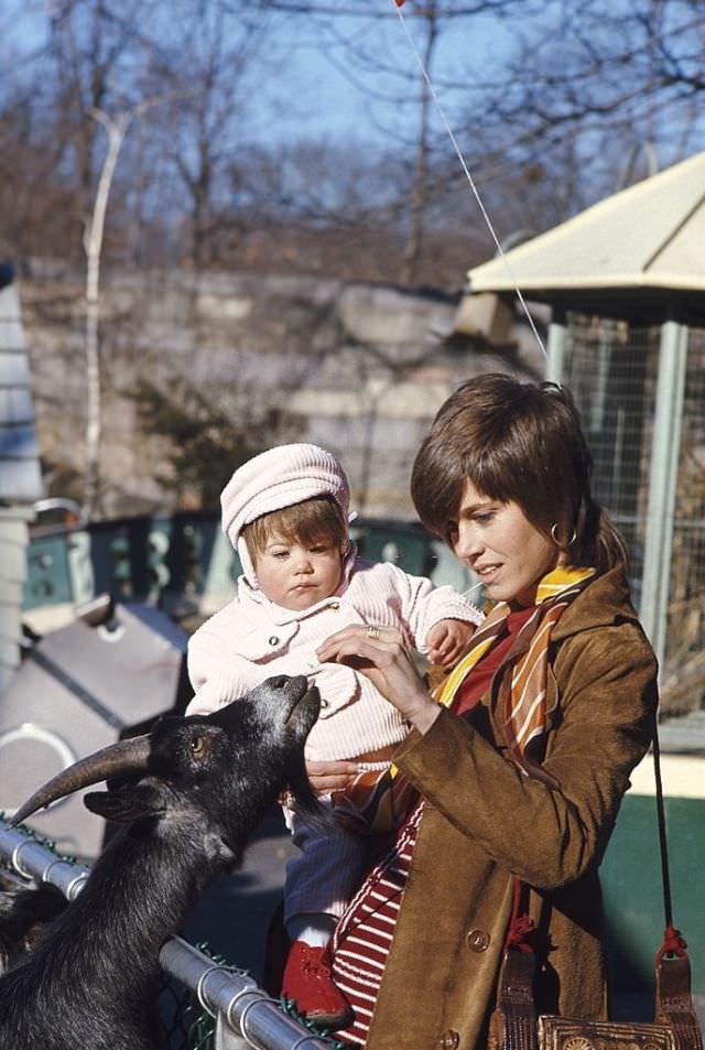 Jane Fonda feding a goat with daughter Vanessa in her arms, Central Park, New York