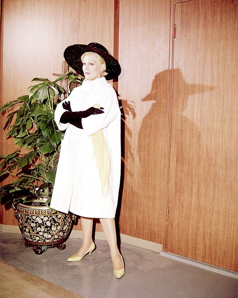 Kim Novak fehér kabátot és fekete, széles karimájú kalapot viselt, 1955 körül