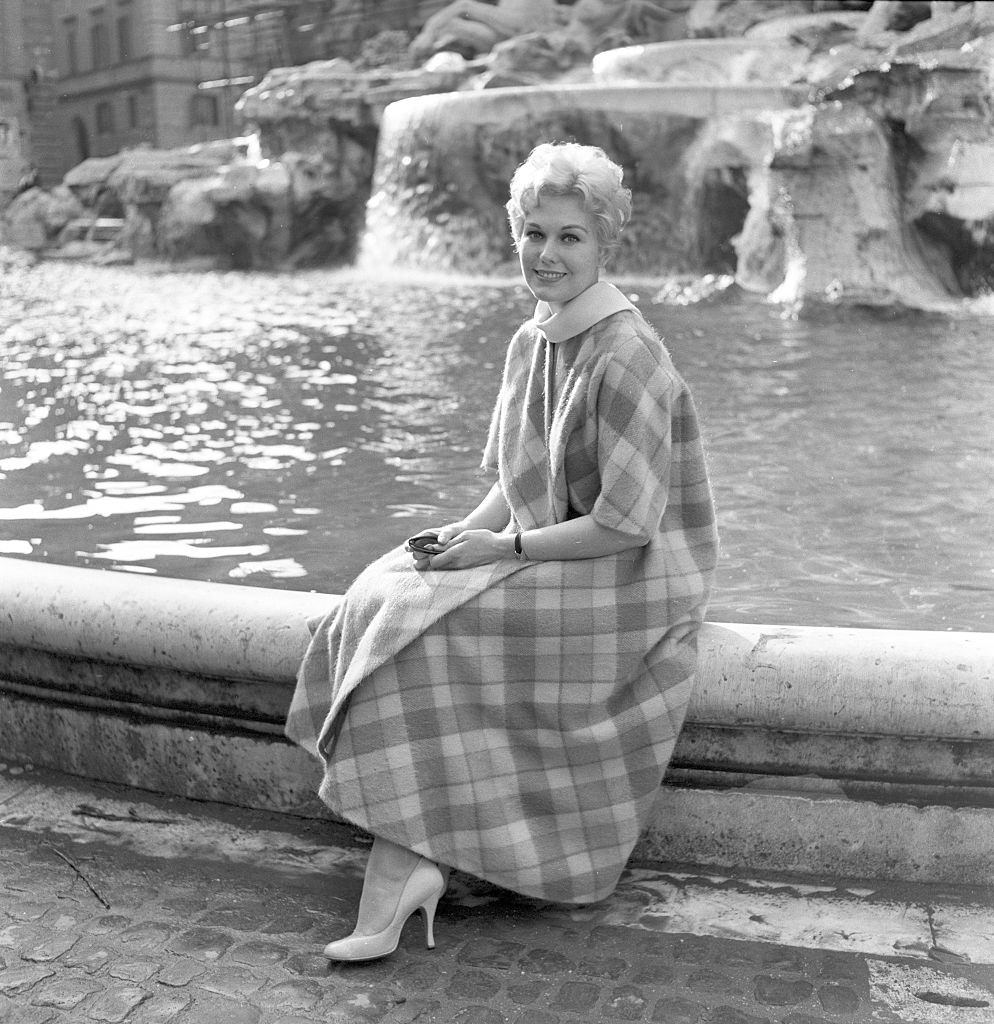 Kim Novak sitting on the edge of the Trevi Fountain, Rome, 1957