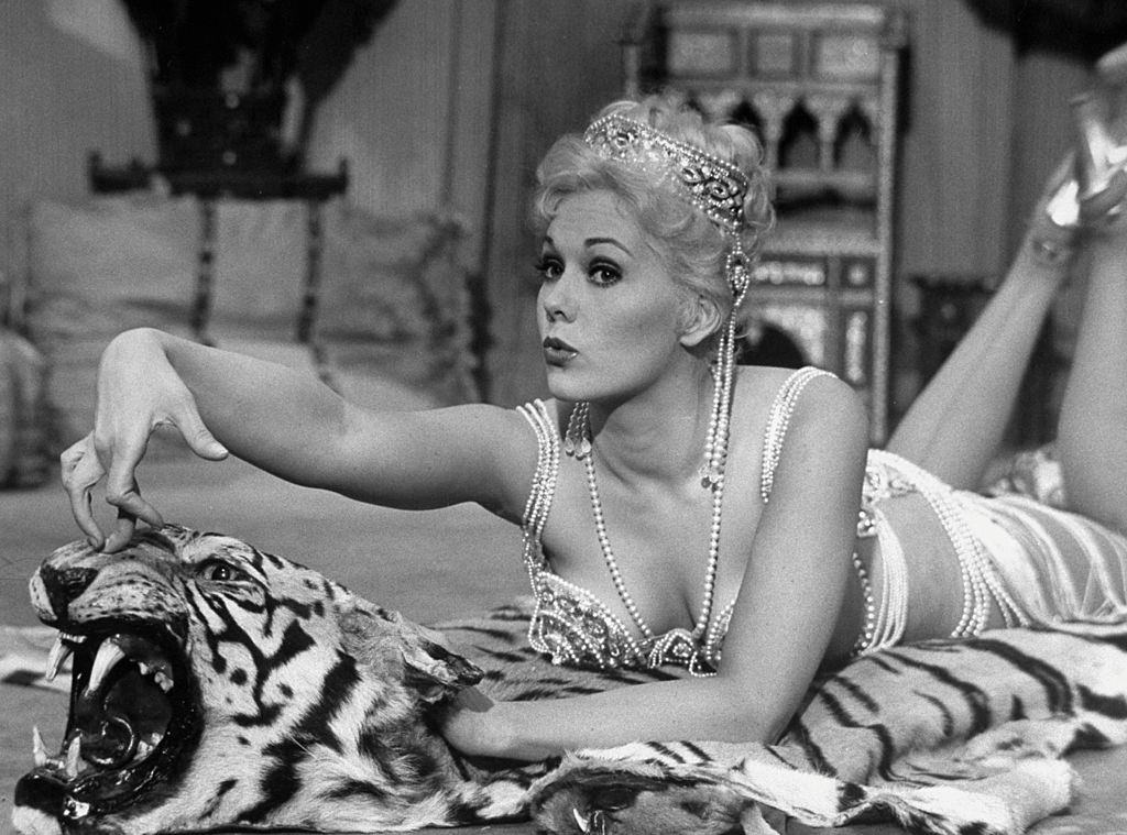 Kim Novak performing hoochie-coochie dance while lolling on tiger rug during carnival tent scene in the movie Jeanne Eagels.