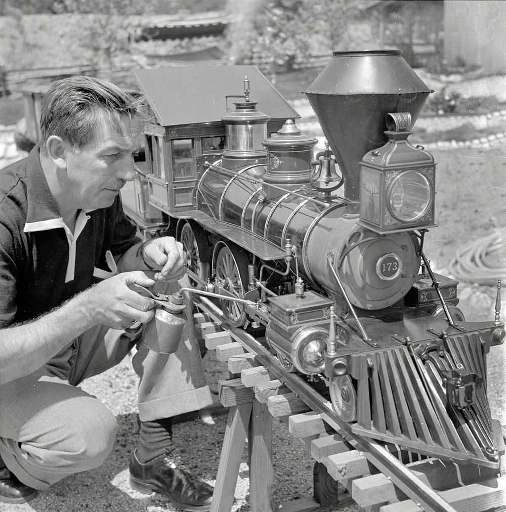 Walt Disney oiling parts of the locomotive of his scale model steam railroad, the Carolwood Pacific Railway, in the backyard of his house in Los Angeles, September 1951