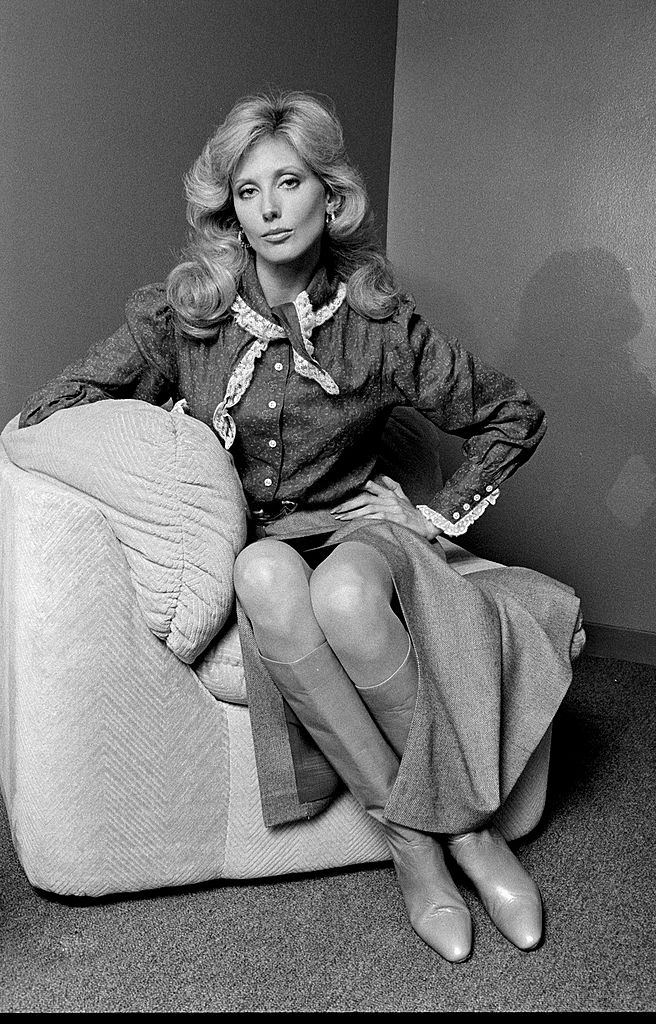 Morgan Fairchild sitting on a sofa
