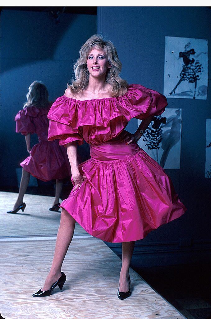 Morgan Fairchild in a pink dress, reflected by mirror