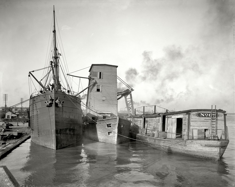 Steamer loading grain from floating elevator, New Orleans waterfront circa 1906.