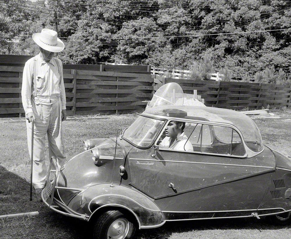 Elvis Presley in 1956 at home in Memphis with his three-wheeled Messerschmitt "bubble car" and Harley-Davidson motorcycle, and grandfather Jessie Presley.
