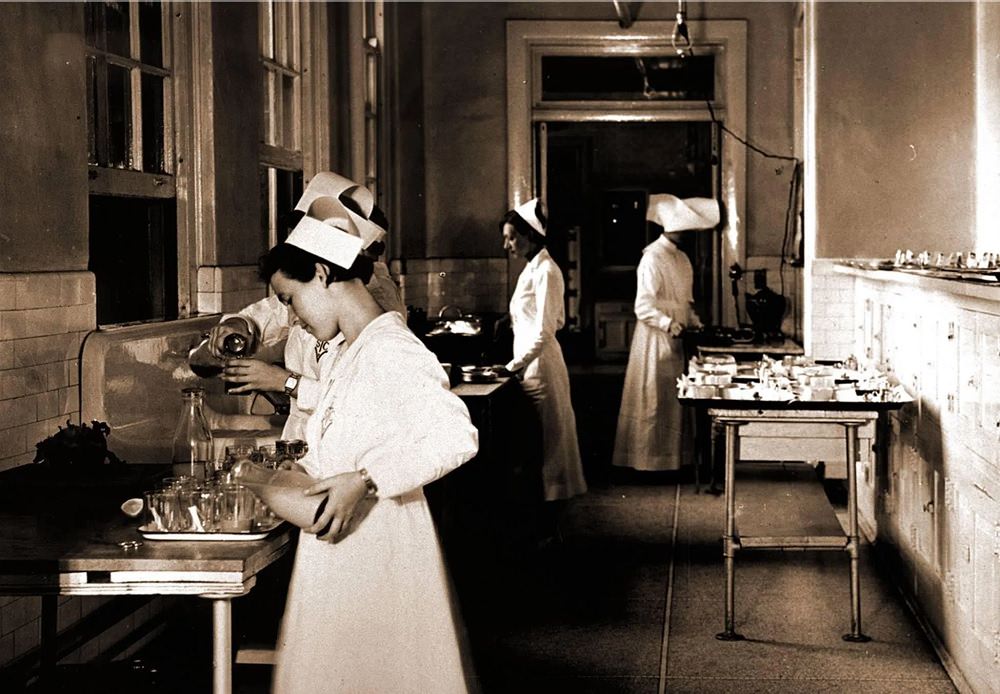 Nurse pouring milk in the glasses for patients at Pensacola Hospital, 1930s