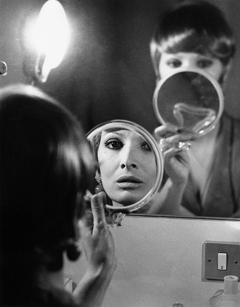 Scilla Gabel looking at herself as a reflection in a puddle in Santo Stefano Square, Milan, 1970s