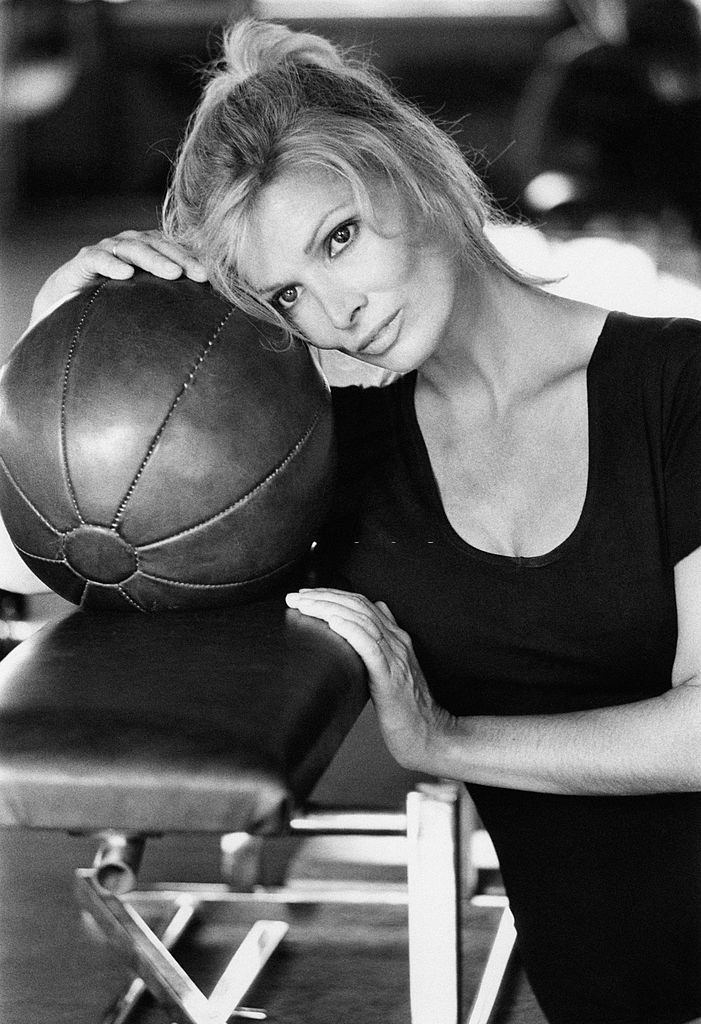 Scilla Gabel leaning on a ball in a gym, 1970s