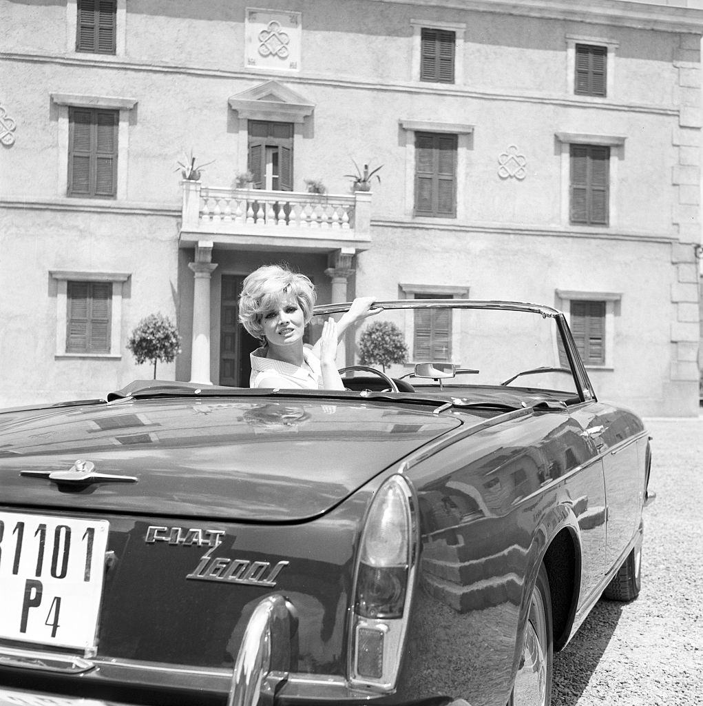 Scilla Gabel in a Fiat 1600 during the filming of "Con rispetto parlando" in Italy, 1965
