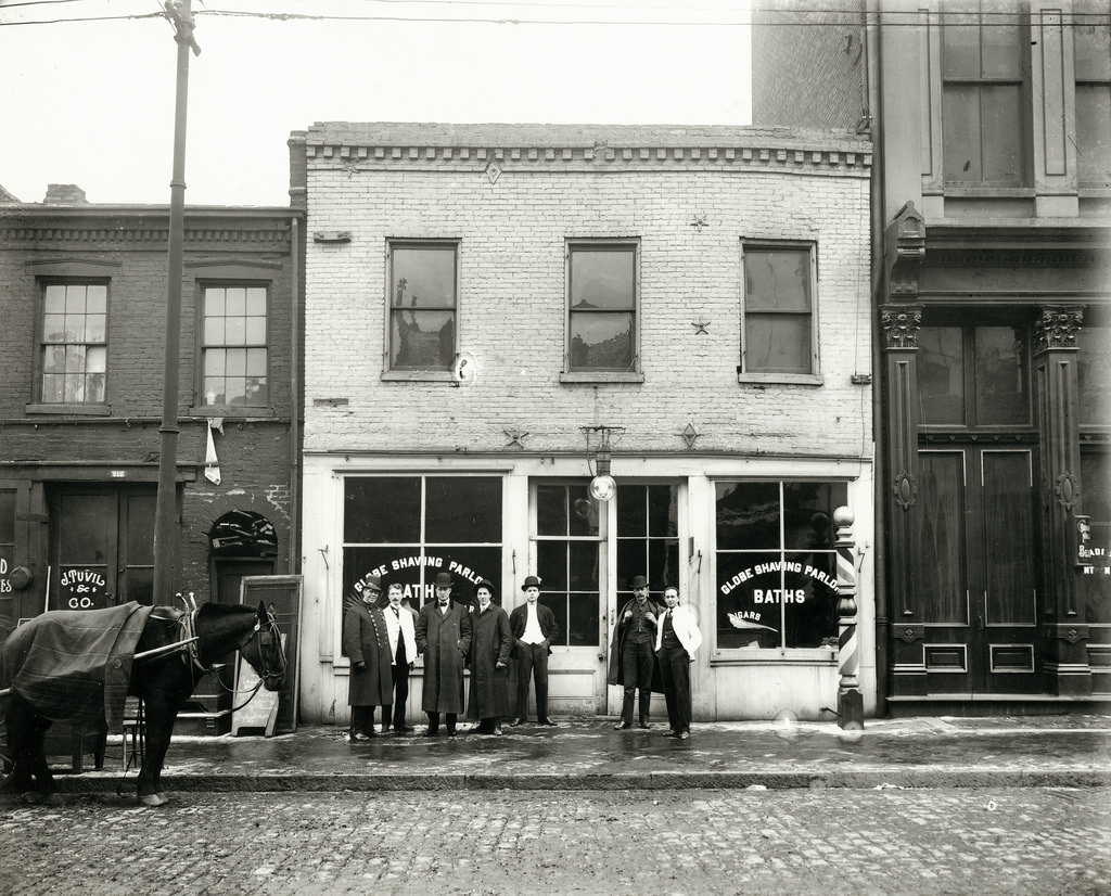 Group of men standing in front of the Globe Shaving Parlor at 1015 Carr, 1910